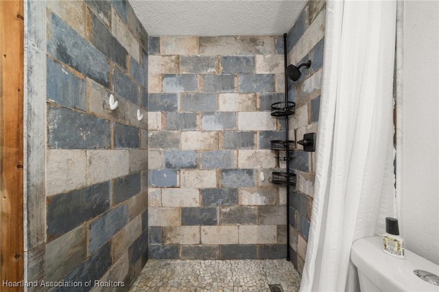 full bathroom with tiled shower, a textured ceiling, and toilet