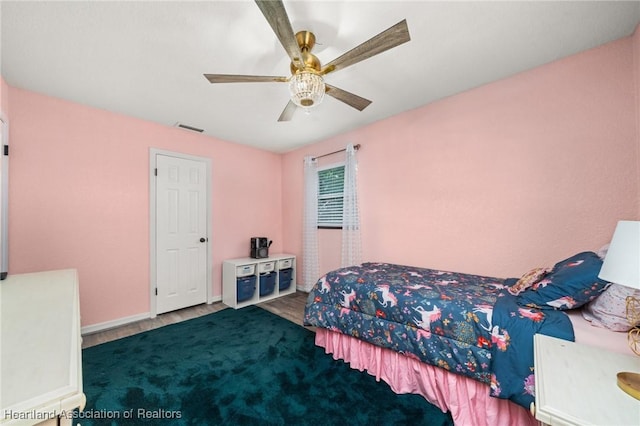 bedroom with baseboards, visible vents, wood finished floors, and ceiling fan
