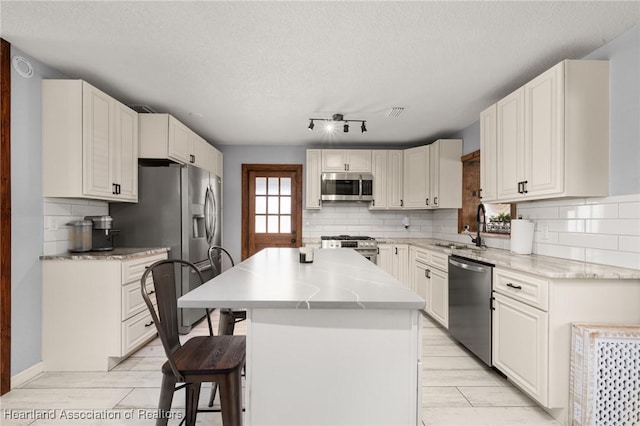 kitchen with a breakfast bar area, tasteful backsplash, a sink, stainless steel appliances, and a kitchen island