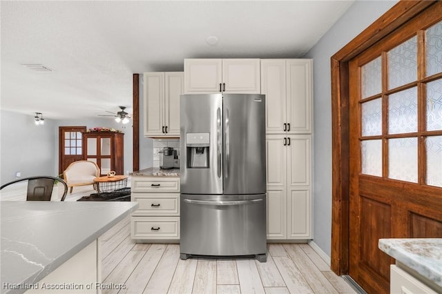 kitchen with a ceiling fan, white cabinets, stainless steel refrigerator with ice dispenser, and light countertops