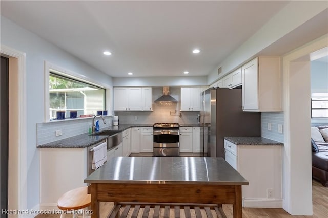 kitchen featuring sink, wall chimney exhaust hood, stainless steel appliances, light hardwood / wood-style flooring, and white cabinets