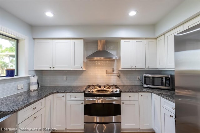 kitchen featuring white cabinets, backsplash, wall chimney range hood, and stainless steel appliances