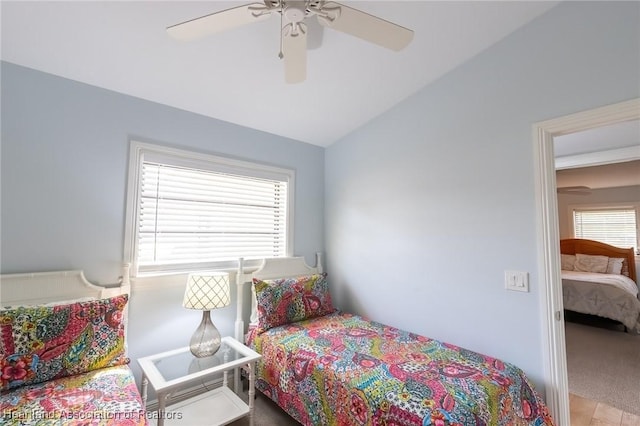 carpeted bedroom featuring multiple windows, vaulted ceiling, and ceiling fan