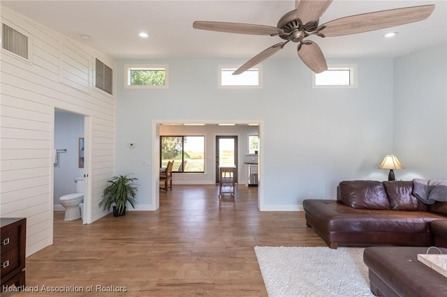 living room with hardwood / wood-style floors, ceiling fan, and a high ceiling