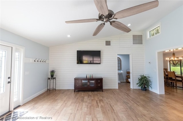 living room featuring light hardwood / wood-style flooring, ceiling fan with notable chandelier, a healthy amount of sunlight, and lofted ceiling