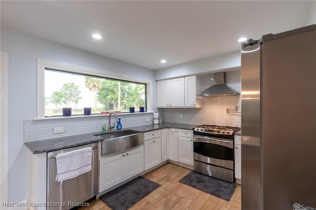 kitchen featuring white cabinetry, sink, stainless steel appliances, and wall chimney range hood