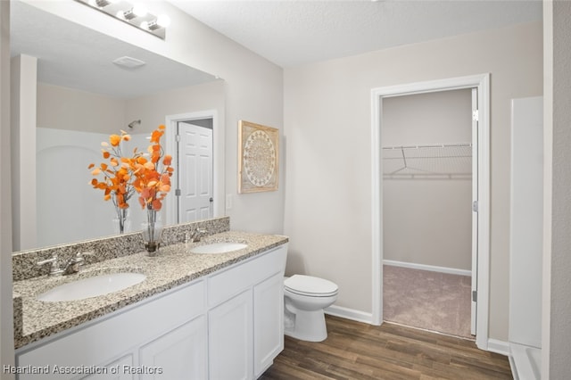 bathroom with wood-type flooring, vanity, a textured ceiling, and toilet