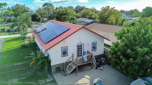 rear view of house with solar panels, a yard, and a patio