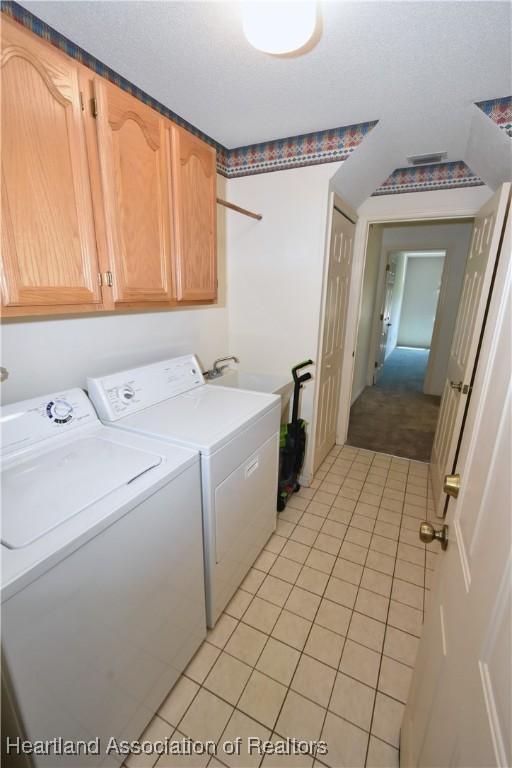 washroom featuring light tile patterned flooring, cabinets, sink, and washing machine and dryer