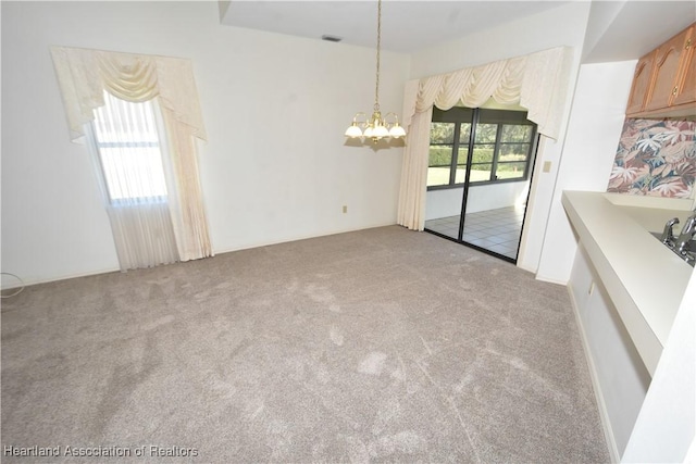 unfurnished dining area with a chandelier, light colored carpet, and a healthy amount of sunlight