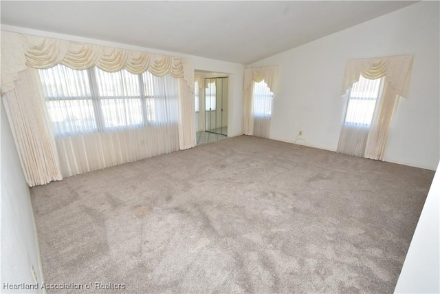 carpeted spare room featuring vaulted ceiling