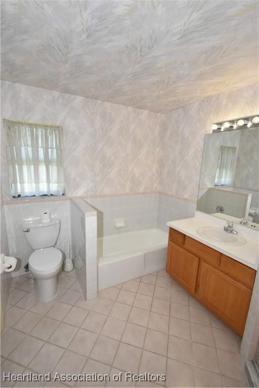 bathroom with tile patterned floors, vanity, tile walls, toilet, and a tub