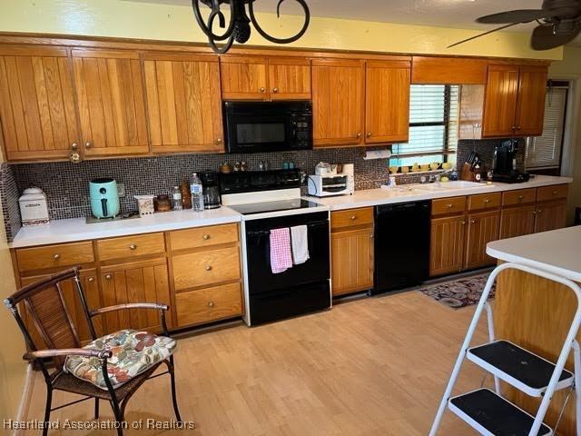 kitchen featuring backsplash, black appliances, sink, ceiling fan, and light wood-type flooring