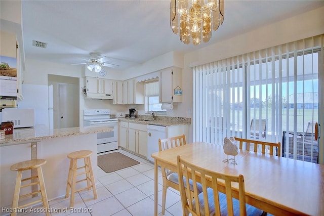 kitchen featuring visible vents, under cabinet range hood, ceiling fan with notable chandelier, white appliances, and a sink
