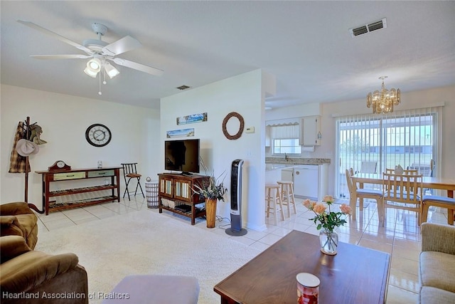 living area featuring light tile patterned floors, visible vents, light carpet, and ceiling fan with notable chandelier