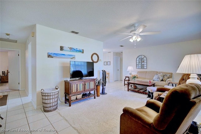 living room with visible vents, a ceiling fan, a textured ceiling, light tile patterned flooring, and light colored carpet