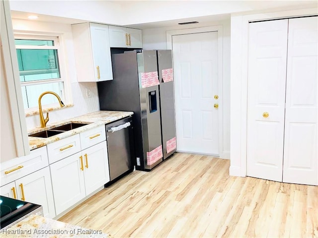 kitchen featuring sink, light hardwood / wood-style flooring, appliances with stainless steel finishes, white cabinetry, and light stone counters