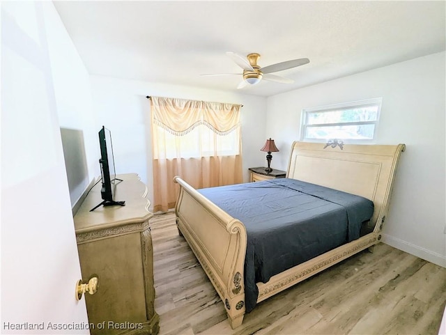 bedroom featuring ceiling fan, multiple windows, and light wood-type flooring