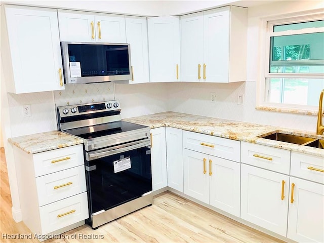 kitchen featuring stainless steel appliances, white cabinetry, sink, and light wood-type flooring