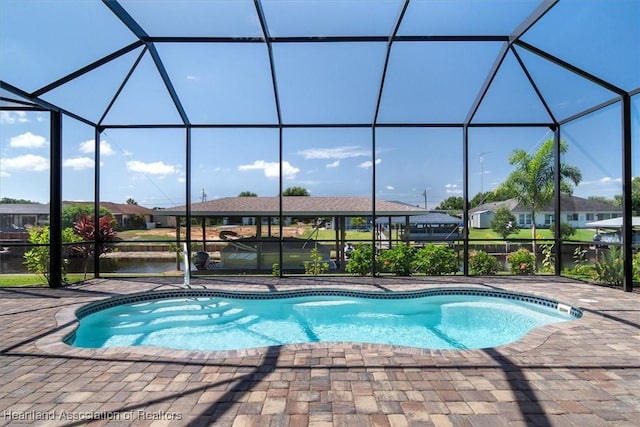 view of swimming pool with a patio area, a lanai, and a water view