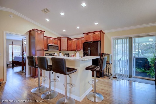 kitchen with a kitchen island, a healthy amount of sunlight, a kitchen bar, and light hardwood / wood-style floors