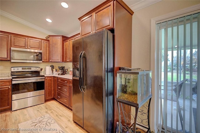 kitchen featuring crown molding, appliances with stainless steel finishes, vaulted ceiling, and light hardwood / wood-style flooring