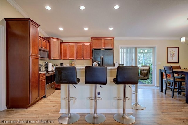 kitchen with stainless steel appliances, light hardwood / wood-style floors, an island with sink, and a breakfast bar area