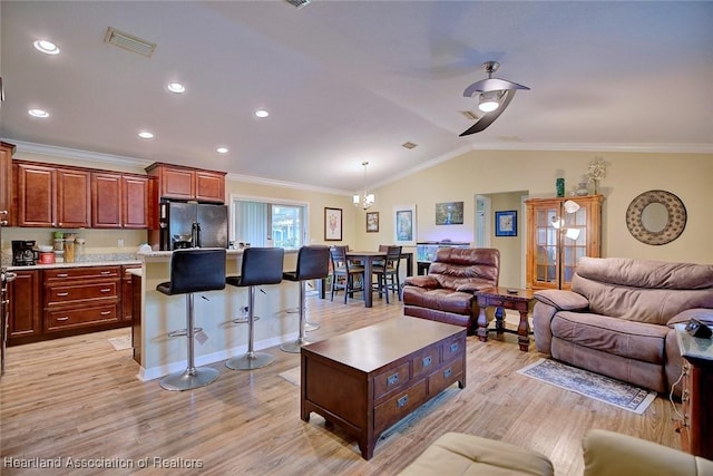 living room featuring an inviting chandelier, lofted ceiling, ornamental molding, and light hardwood / wood-style floors