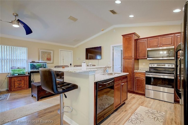 kitchen with appliances with stainless steel finishes, lofted ceiling, sink, a kitchen breakfast bar, and a kitchen island with sink