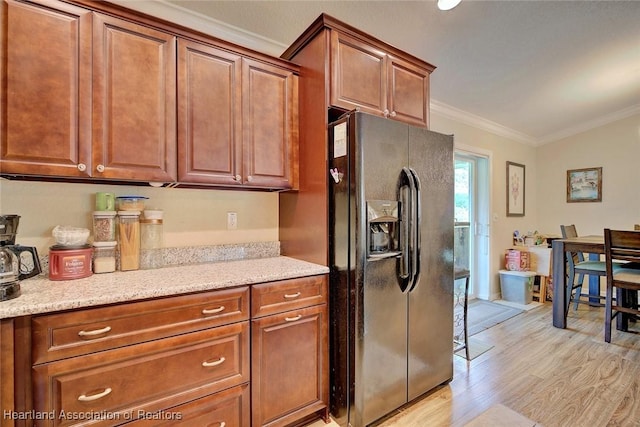 kitchen with black fridge, crown molding, light stone countertops, and light hardwood / wood-style flooring