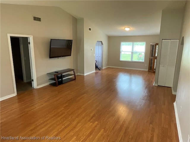 unfurnished living room featuring lofted ceiling, wood finished floors, and baseboards