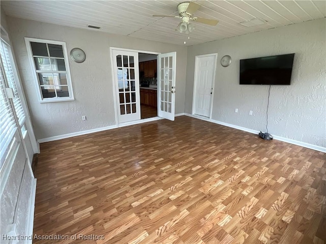 unfurnished living room with a ceiling fan, wood finished floors, baseboards, french doors, and wood ceiling