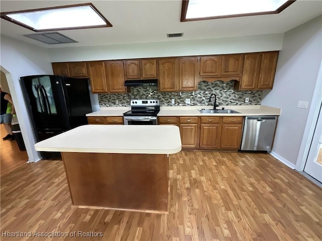kitchen featuring appliances with stainless steel finishes, a sink, light wood-style floors, and light countertops