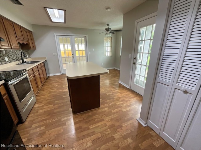 kitchen featuring a sink, stainless steel appliances, light wood-style flooring, backsplash, and light countertops