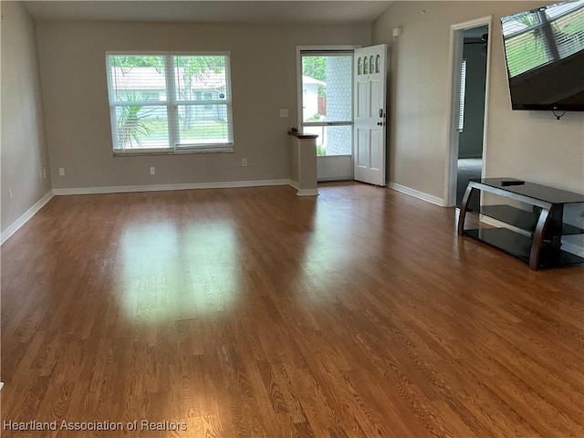 unfurnished living room featuring wood finished floors and baseboards