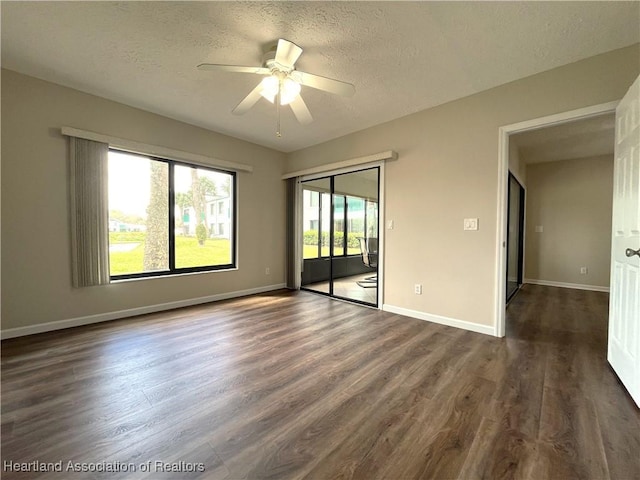 unfurnished room with a ceiling fan, a textured ceiling, baseboards, and dark wood-type flooring