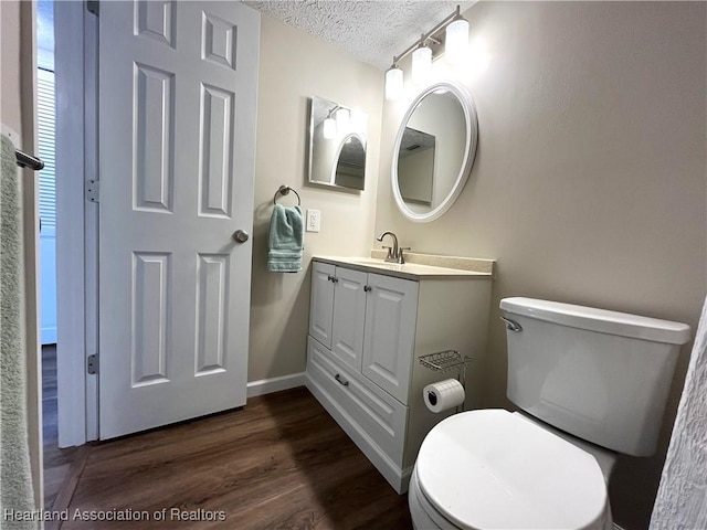 bathroom featuring vanity, a textured ceiling, toilet, and wood finished floors