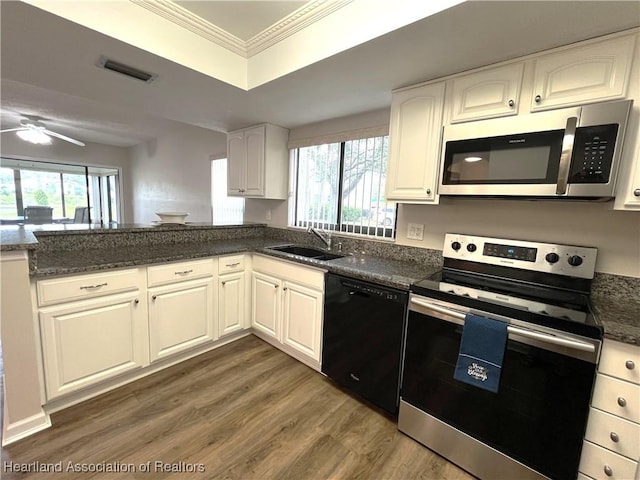 kitchen with wood finished floors, a sink, visible vents, ornamental molding, and appliances with stainless steel finishes