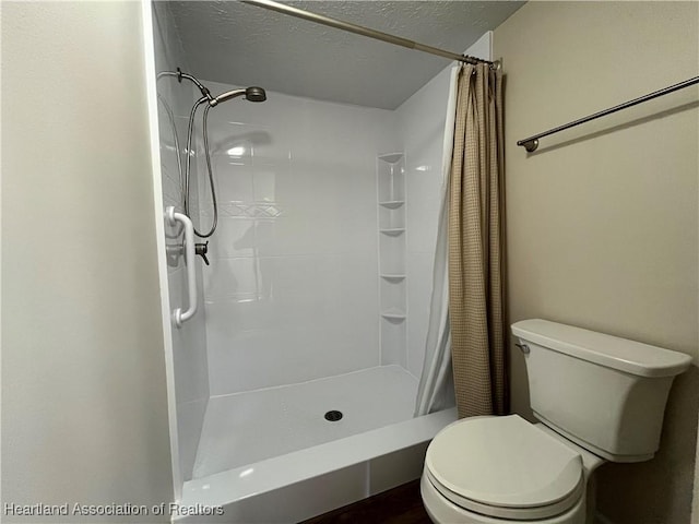 bathroom with a textured ceiling, a shower stall, and toilet