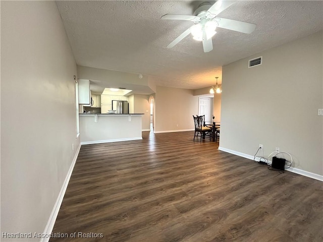 unfurnished living room with dark wood-type flooring, visible vents, a textured ceiling, and baseboards