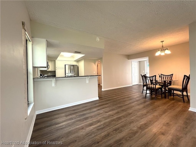 dining area featuring an inviting chandelier, a textured ceiling, baseboards, and dark wood-type flooring