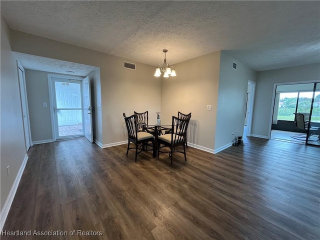 dining area featuring a textured ceiling, dark wood-type flooring, visible vents, baseboards, and an inviting chandelier