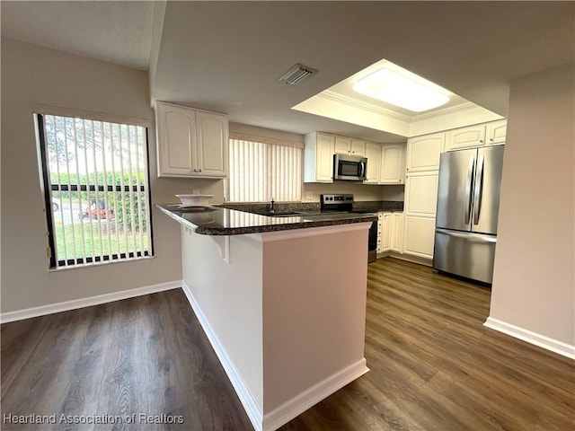 kitchen featuring a peninsula, visible vents, baseboards, white cabinets, and appliances with stainless steel finishes