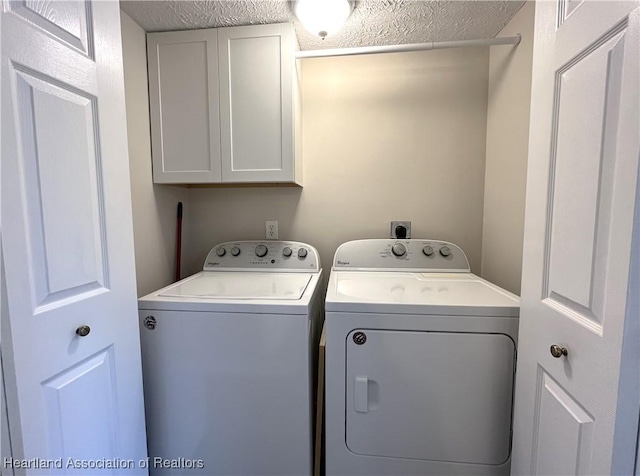 clothes washing area with cabinet space, a textured ceiling, and washing machine and clothes dryer