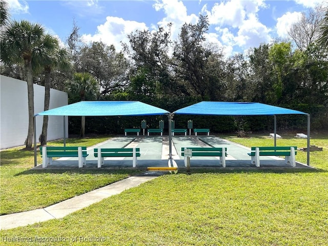 view of property's community featuring fence, shuffleboard, and a lawn