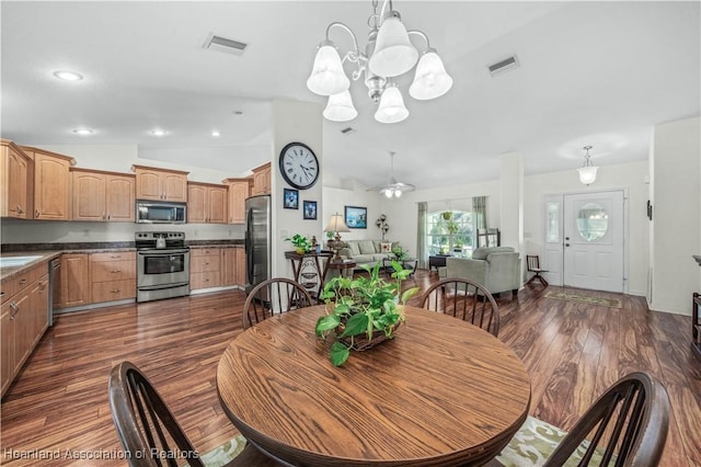 dining space featuring lofted ceiling, visible vents, dark wood finished floors, and ceiling fan with notable chandelier