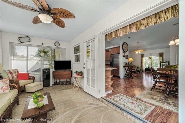 living area featuring wood finished floors and ceiling fan with notable chandelier