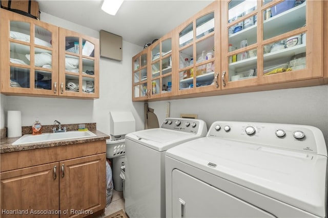 laundry room with cabinet space, separate washer and dryer, and a sink