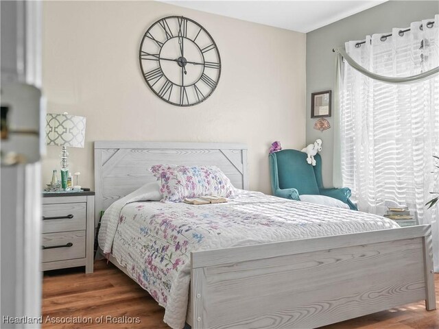 bedroom featuring multiple windows and dark hardwood / wood-style flooring