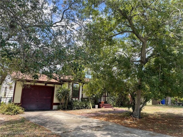 16 Notre Dame St, Lake Placid, FL 33852 - view of property hidden behind natural elements with a garage and driveway